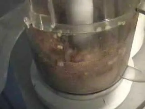 Food processor in use with blended ingredients inside.