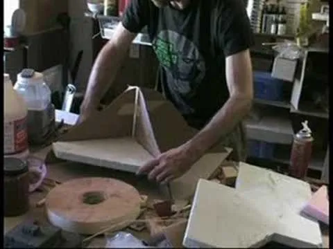Person working on a cardboard model in a workshop.