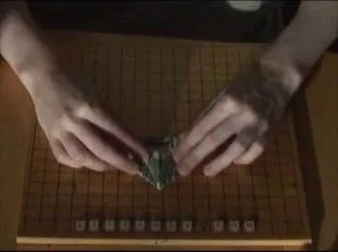 Hands manipulating a game piece on a Go board.