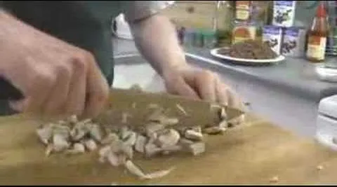 Person chopping mushrooms on a wooden cutting board.