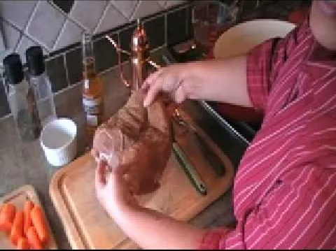 A person unwrapping a brown paper package in a kitchen setting.