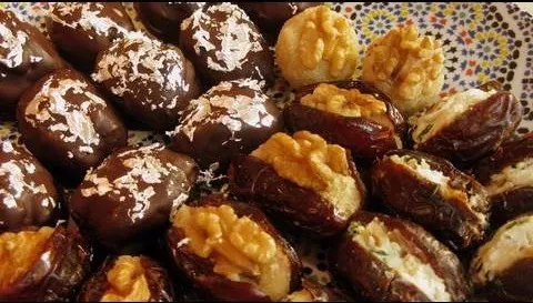Assorted chocolate-covered and nut-stuffed dates on a decorative plate.