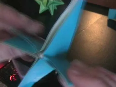 Blue origami paper being folded into a butterfly shape.