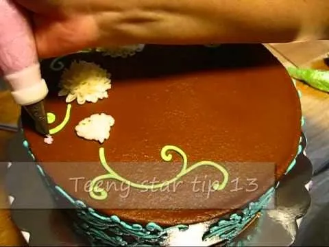 Decorating a chocolate cake with piping techniques and floral designs.