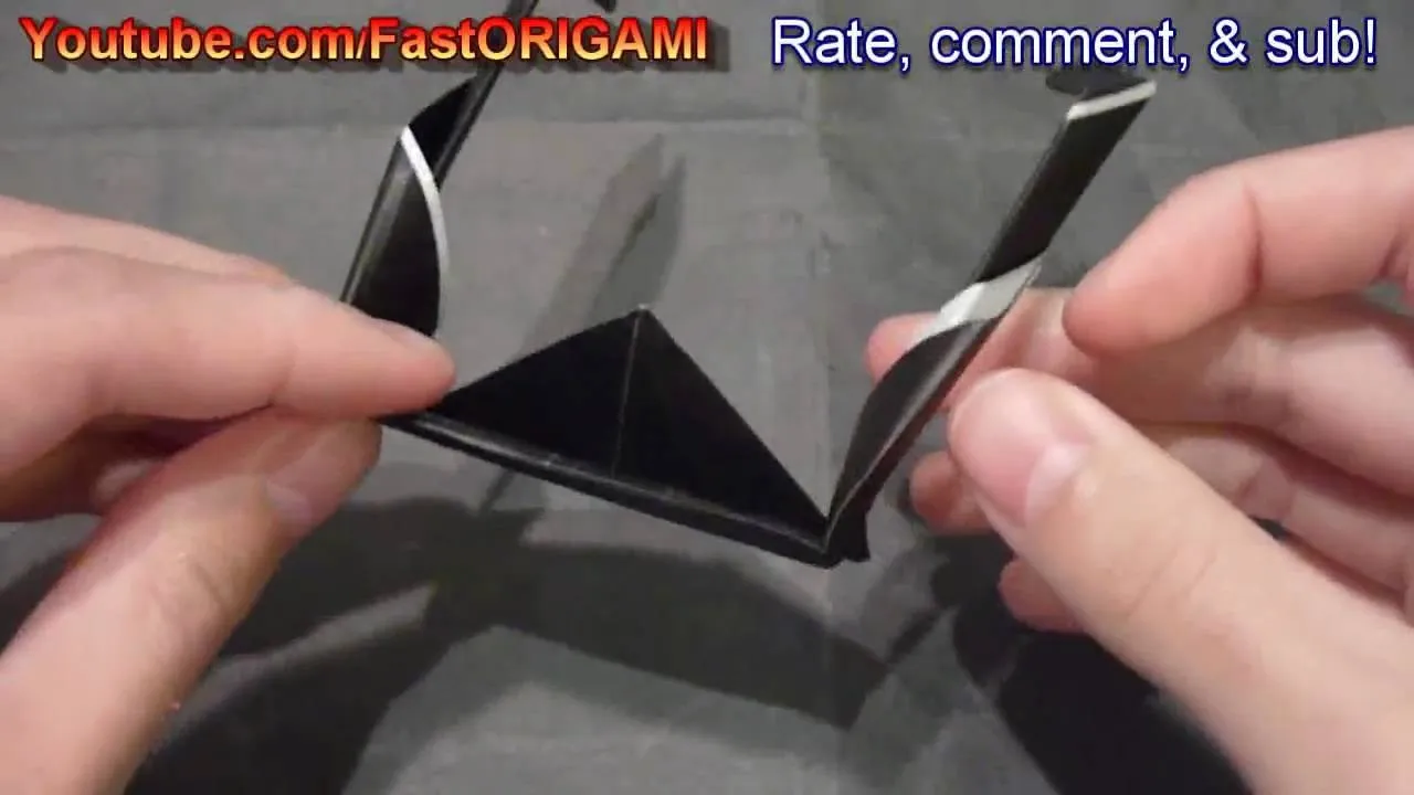 Hand folding a black origami figure.