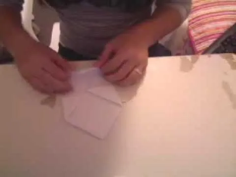 Hands folding paper on a table.
