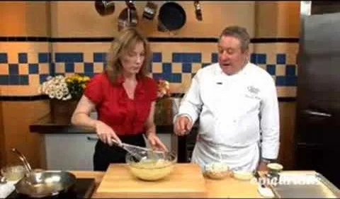 Chef demonstrating cooking techniques with a female assistant in a kitchen setting.