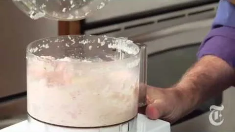 A person blending ingredients in a food processor.