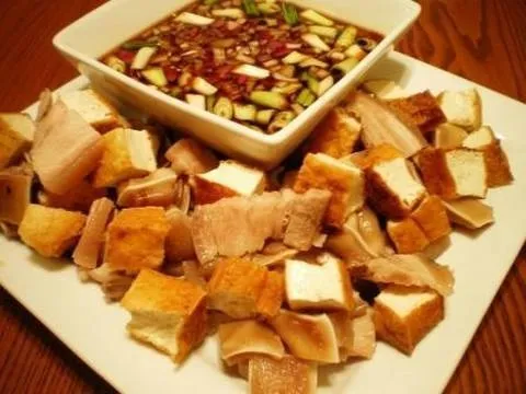 Appetizing platter of marinated meats and a dipping sauce with diced vegetables.