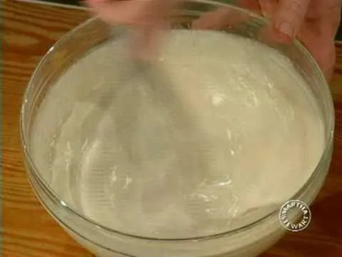 Whisking a creamy mixture in a glass bowl.
