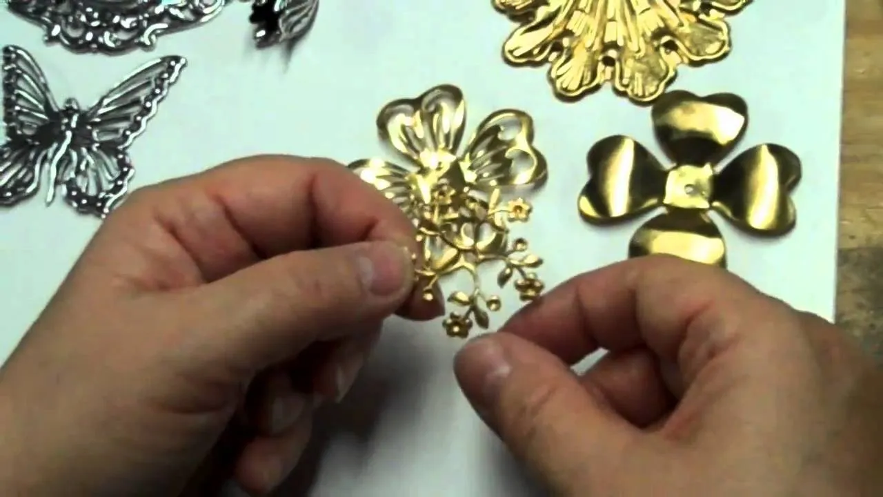 Hand holding gold metal floral embellishments on a white background.