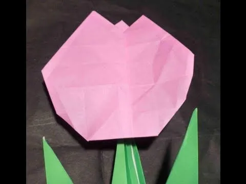 Pink origami flower with green leaves.