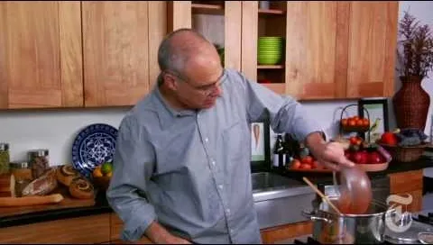 A person cooking in a modern kitchen, stirring a pot on the stove.
