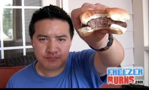 A person holding a hamburger in front of them.