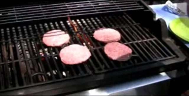 Fresh hamburger patties grilling on a barbecue.