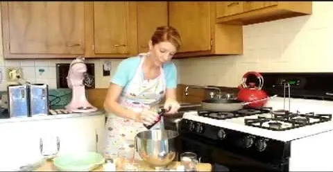 Woman cooking in a kitchen using a mixer.