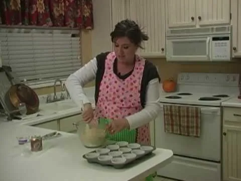 Woman wearing an apron mixing batter in a kitchen.