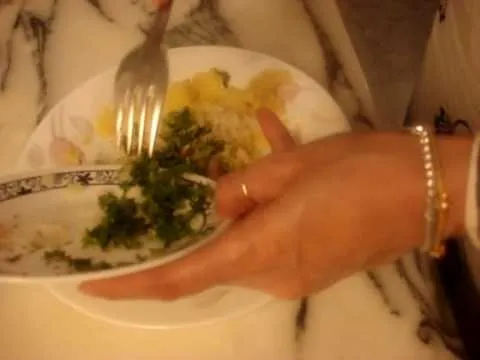 A plate of food being served, featuring rice and green vegetables, with a fork in hand.