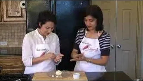 Two women in aprons preparing food in a kitchen.