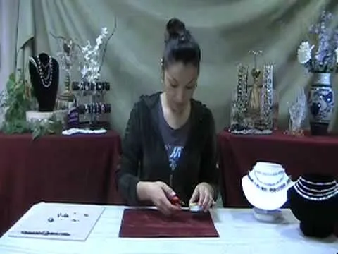 Woman crafting jewelry at a table with various accessories displayed.