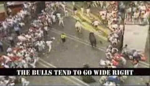 Participants running from bulls in a crowded street during a festival.