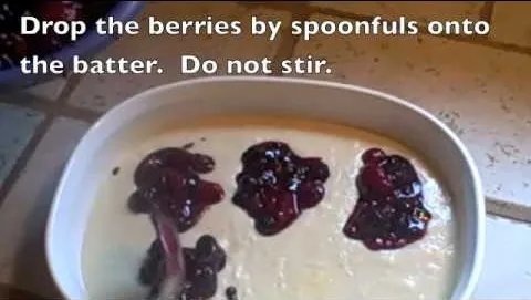 Adding berries to batter in a baking dish.