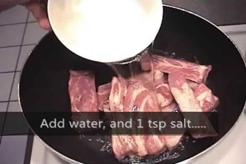 Adding water and salt to meat in a frying pan.