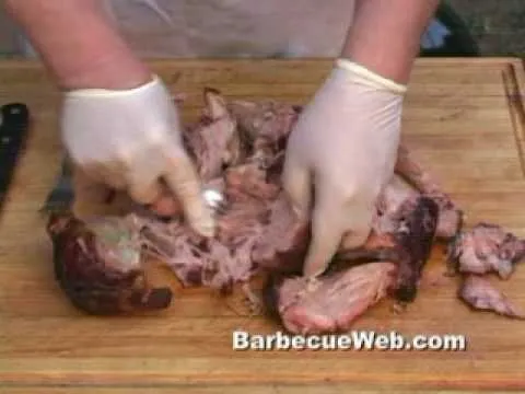 Prepared barbecue meat being sliced on a wooden cutting board.