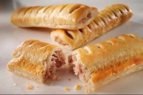Savory pastry filled with meat, cut in half, showcasing flaky crust.