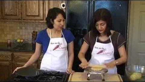 Two women in aprons preparing food in a kitchen.