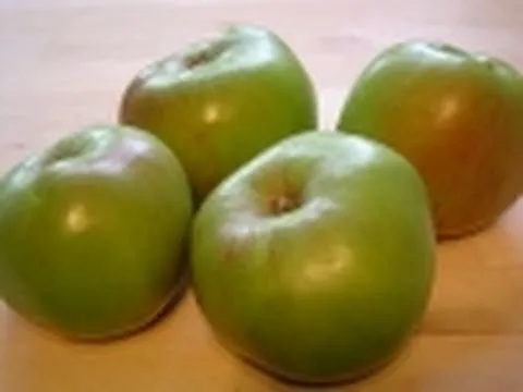 Fresh green apples arranged on a wooden surface.