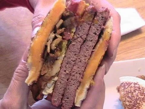 Layered hamburger with multiple patties and cheese.