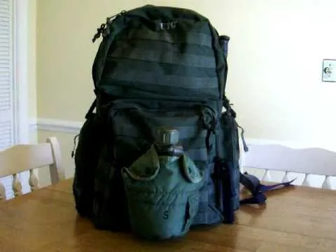 Military-style black backpack on a wooden table.