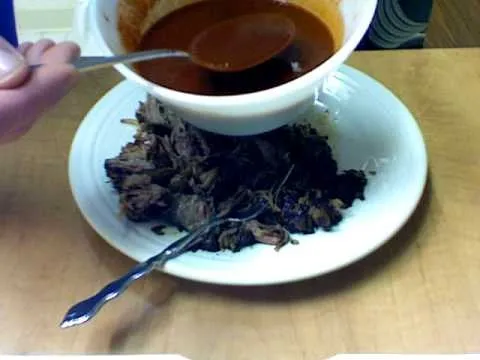 Beef dish being served with sauce on a plate.