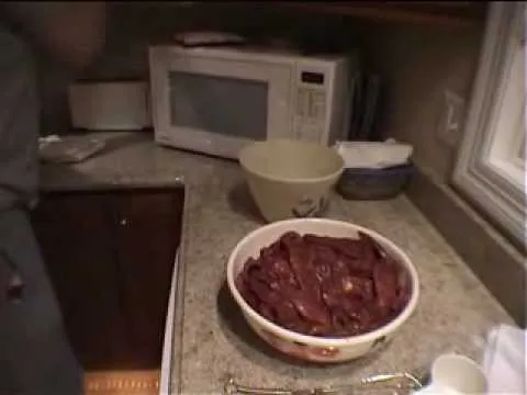 Bowl of cooked meat on a kitchen counter with a microwave in the background.