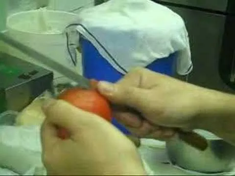 Person peeling a red tomato in a kitchen setting.