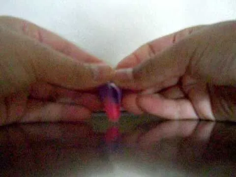 Hands demonstrating a handcraft involving a small object.