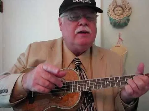 Man playing a ukulele while wearing a suit and a cap.