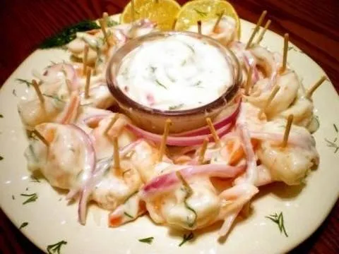 Shrimp cocktail served with dipping sauce and lemon wedges.