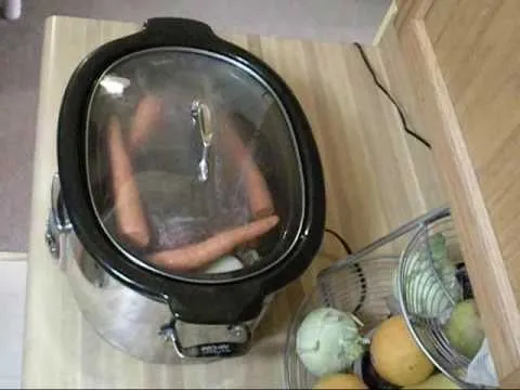 Slow cooker with carrots on a wooden countertop.