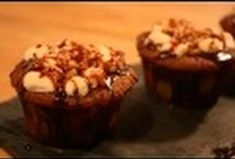 Delicious chocolate cupcakes topped with nuts and chocolate drizzle.
