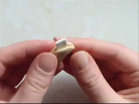 Hand holding a small clay model with a metallic detail.