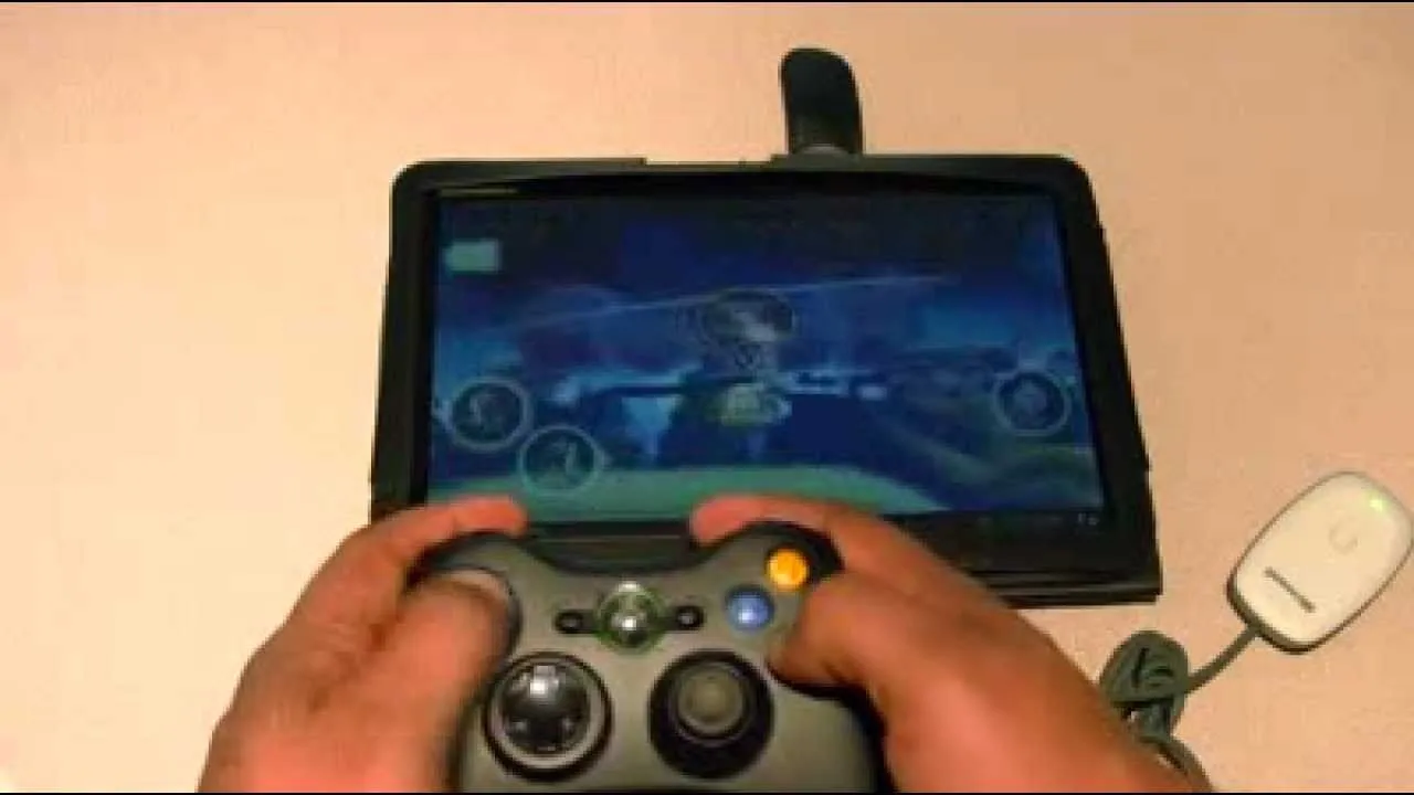 Person holding a game controller while playing a video game on a tablet.