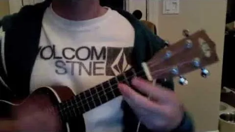Person playing a ukulele while wearing a branded t-shirt.