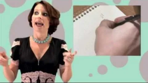 Woman speaking while holding a pen, with a handwritten note on a notebook.