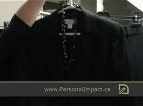 A black business suit jacket hanging on a clothing rack.