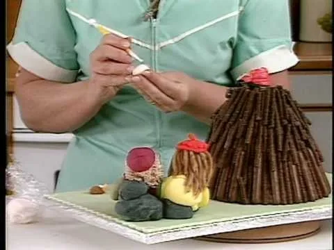 Volcano-shaped cake being decorated with miniature figures.