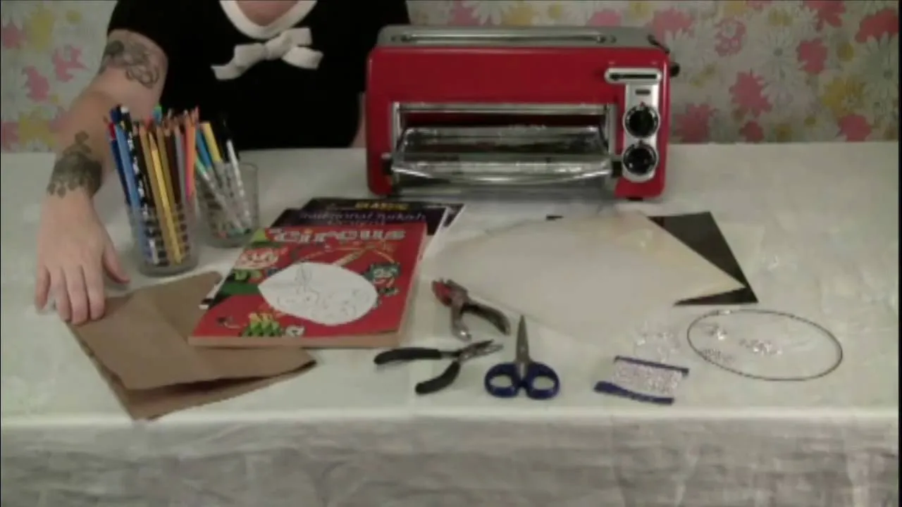Crafting materials and a red toaster oven on a table.