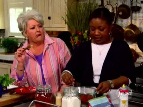 Two women cooking together in a kitchen, one stirring a bowl while the other observes.