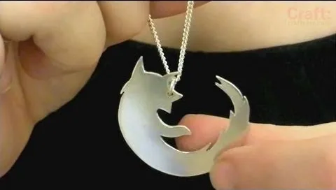 Silver cat silhouette necklace being held.